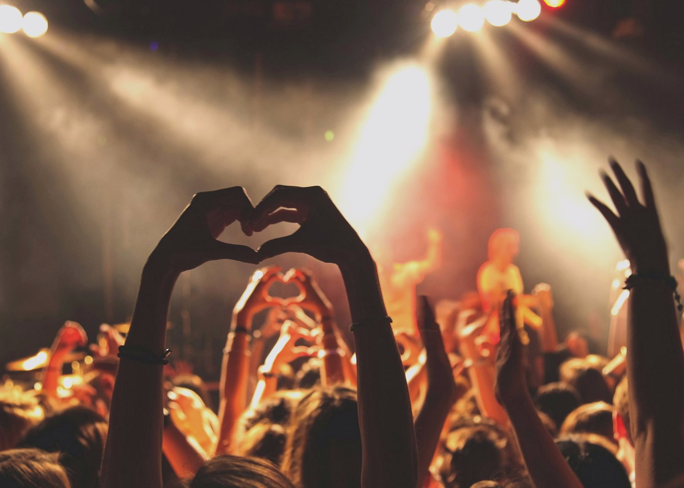 Crowd at a live show making heart shapes with their hands