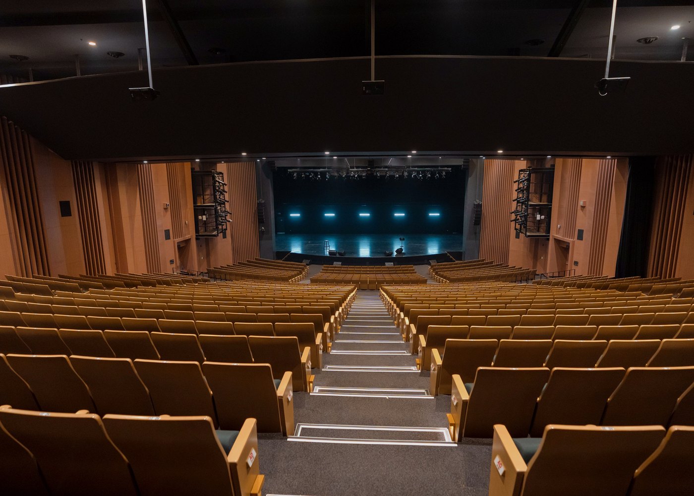Modern theatre auditorium with wooden seats looking toward a lit stage