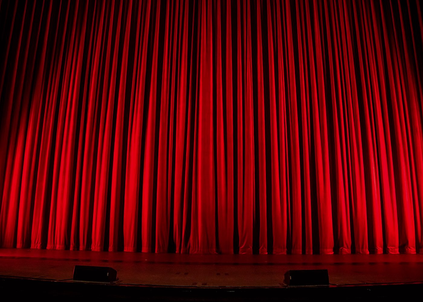 Closed red curtain on an empty theatre stage