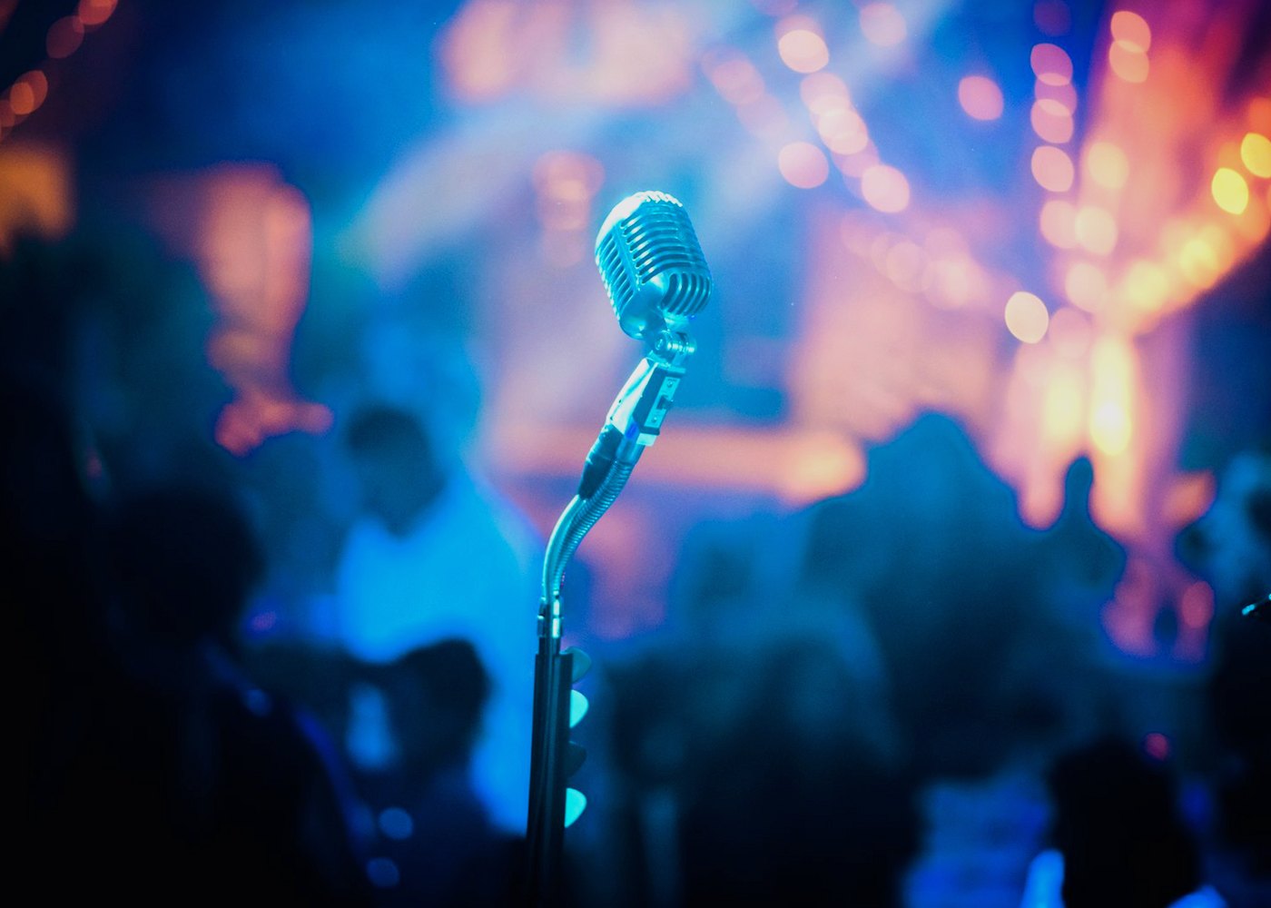 Vintage microphone in front of a live crowd and blue stage lights